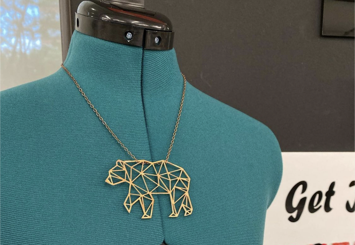 A necklace place on a mannequin. The necklace is a bear made from a PBC board.